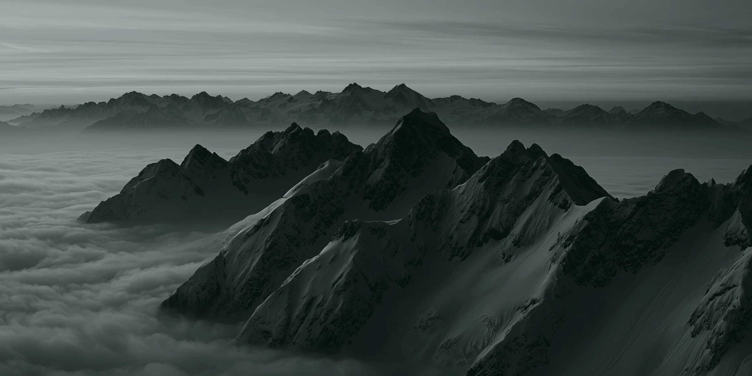 A mountain range at night under a teal sky